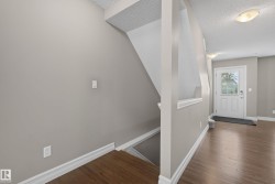 Foyer entry with wood-finish flooring, white paneled door with glass insert, and neutral wall tones - 