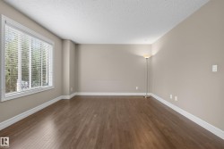 Spacious interior room featuring wood-finish flooring, neutral wall tones, and extensive baseboards - 