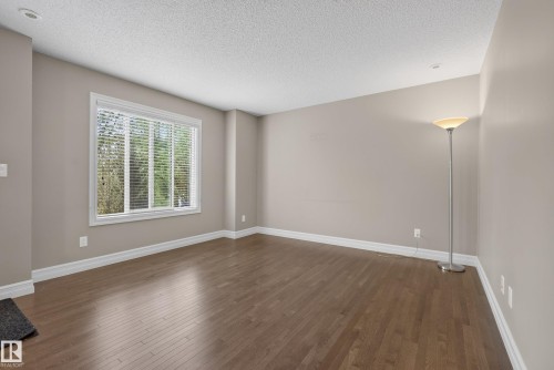 Spacious room featuring wood-finish flooring, neutral-toned walls, and white baseboards - 53 3625 144 Avenue, Edmonton, AB 