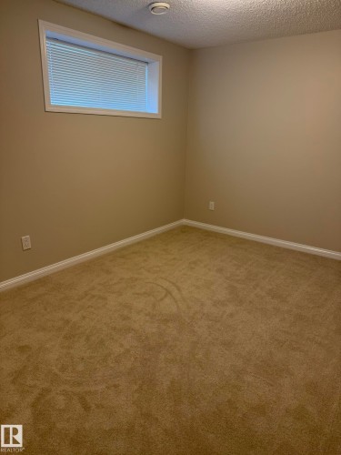 Room featuring neutral tone carpeting, painted walls, white baseboards, and a window with blinds - 8305 Ellis Crescent Nw, Edmonton, AB 