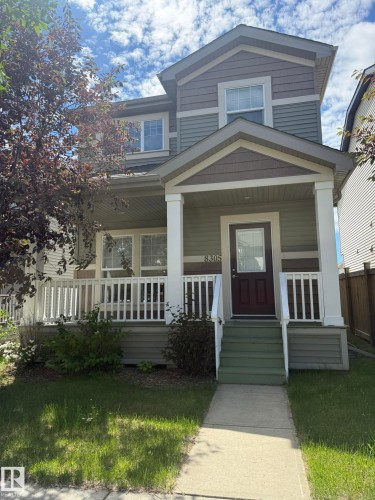 Two-story residence featuring a covered front porch with white railing, multi-toned horizontal siding, and a dark paneled front door - 8305 Ellis Crescent Nw, Edmonton, AB 