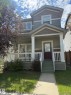 Two-story residence featuring a covered front porch with white railing, multi-toned horizontal siding, and a dark paneled front door - 8305 Ellis Crescent Nw, Edmonton, AB 
