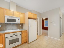 Kitchen area featuring light wood cabinetry, white appliances, and a tiled backsplash - 