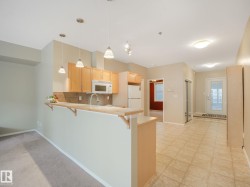 Open-concept kitchen featuring wood cabinetry, stainless steel sink, and a breakfast bar with pendant lighting - 