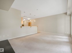 Spacious living area featuring light-colored carpeting and neutral wall tones - 