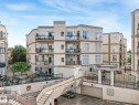 Multi-story residential building featuring balconies with glass railings, stucco exterior, and an integrated parking garage - 150 4827 104A Street, Edmonton, AB 