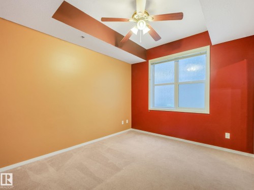 Bright room featuring neutral carpeting, a large window, and a ceiling fan with light fixture - 150 4827 104A Street, Edmonton, AB 