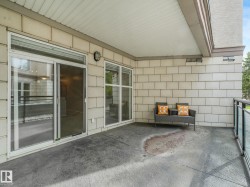Private covered patio featuring a stamped concrete surface and glass panel railing - 