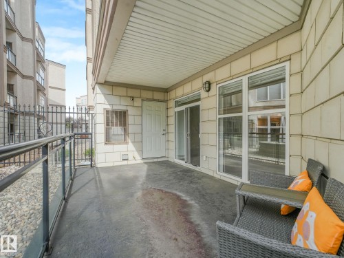 Private patio featuring concrete flooring, a glass and metal railing, a sliding glass door, and a paneled entry door - 150 4827 104A Street, Edmonton, AB 