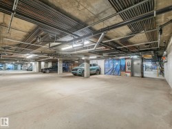 Concrete flooring and exposed overhead utilities characterize this subterranean parking area - 