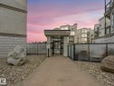 Gated entry featuring decorative wrought ironwork, concrete pathway, and surrounding gravel landscaping with large boulders - 150 4827 104A Street, Edmonton, AB 