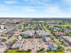 Aerial perspective showcasing a mixed-use urban landscape featuring commercial structures, multi-story residential buildings, and extensive paved parking areas - 