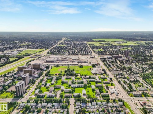 Aerial perspective showcasing a mixed-use district with low-rise and high-rise residential buildings, commercial structures, and extensive green spaces - 150 4827 104A Street, Edmonton, AB 