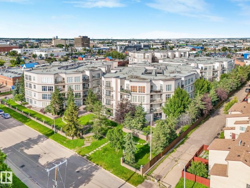 Multi-story residential buildings featuring contemporary architecture with numerous balconies, perimeter landscaping, and a surrounding urban environment - 150 4827 104A Street, Edmonton, AB 