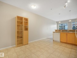 Kitchen area featuring light wood-finish cabinetry, a double basin sink, and an integrated white dishwasher - 