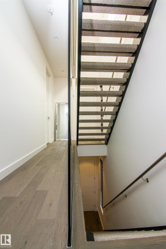 Modern staircase featuring open risers, metal railings, and carpeted treads - 13218 102 Avenue, Edmonton, AB 