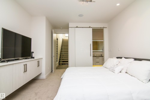 Bedroom featuring a sliding barn door, wall-mounted cabinetry, integrated lighting, and carpet flooring - 13218 102 Avenue, Edmonton, AB 