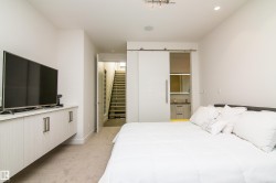 Bedroom featuring a sliding barn door, wall-mounted cabinetry, integrated lighting, and carpet flooring - 