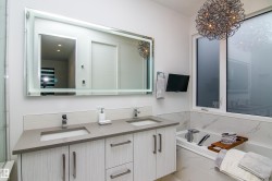 Bathroom featuring a dual vanity with undermount sinks, quartz countertop, and white wood-finish cabinetry - 