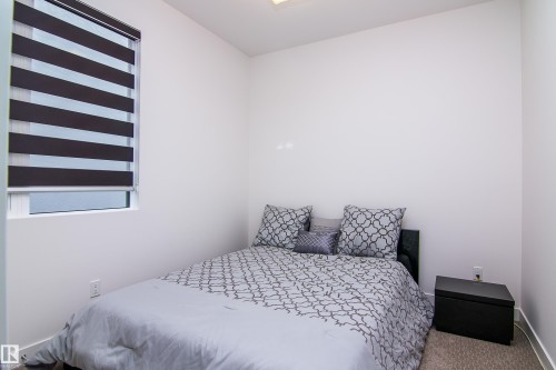 Room featuring a single window with banded shades, carpeted flooring, and a ceiling-mounted light fixture - 13218 102 Avenue, Edmonton, AB 