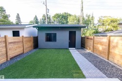 Detached accessory building with a dark shingled roof and grey stucco exterior - 