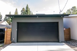 Detached garage with a dark sectional door and gray stucco exterior - 