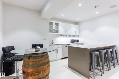 Contemporary kitchen area featuring white cabinetry, a large center island with seating, a built-in dishwasher, and recessed lighting - 13218 102 Avenue, Edmonton, AB 