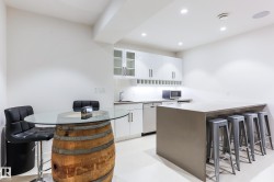 Contemporary kitchen area featuring white cabinetry, a large center island with seating, a built-in dishwasher, and recessed lighting - 