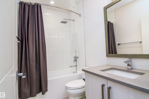 Modern bathroom featuring a contemporary vanity with a chrome faucet, undermount sink, and light-toned countertop - 13218 102 Avenue, Edmonton, AB 