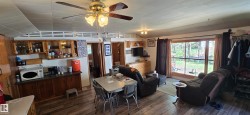 Open concept living area featuring wood-finish flooring and a ceiling fan with integrated lighting - 