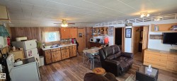 Open concept living space featuring wood-finish flooring, wood paneling, and a ceiling fan - 