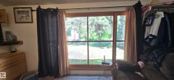 Large picture window with wood-finish trim and a wooded outdoor setting - 