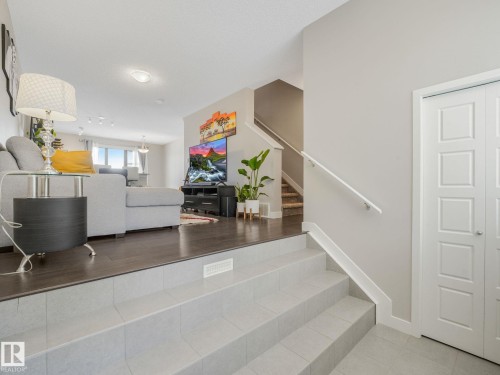 Split-level entry featuring light gray floor tiles and a white handrail - 55 4470 Prowse Road, Edmonton, AB 