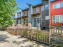 Modern townhome exterior featuring multi-toned siding, a teal entry door, and a private fenced front yard - 55 4470 Prowse Road, Edmonton, AB 