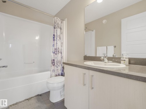 Full bathroom featuring a white tub/shower combination, white toilet, and a vanity with a white basin sink, polished chrome faucet, and integrated countertop - 55 4470 Prowse Road, Edmonton, AB 
