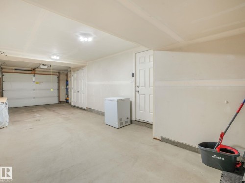 Attached two-car garage featuring a concrete floor, overhead lighting, and an access door - 55 4470 Prowse Road, Edmonton, AB 