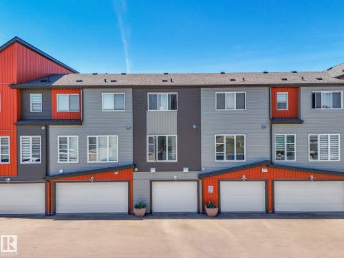 Modern townhouse exterior featuring multi-toned siding in gray, charcoal, and vibrant orange accents - 55 4470 Prowse Road, Edmonton, AB 