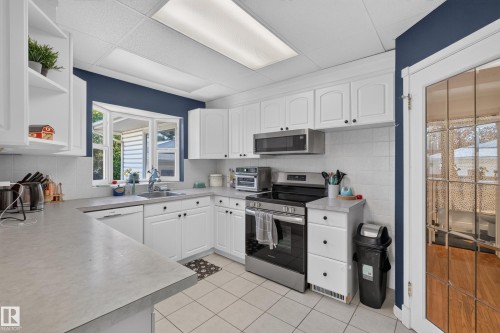 Modern kitchen featuring white cabinetry, light-toned countertops, and a white tile backsplash - 11015 122 Street, Edmonton, AB 