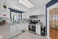 Modern kitchen featuring white cabinetry, light-toned countertops, and a white tile backsplash - 