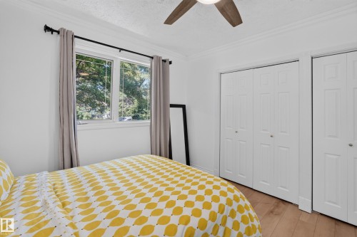 Bedroom featuring wood-finish flooring, a window with exterior tree-line scenery, and a ceiling fan with integrated lighting - 11015 122 Street, Edmonton, AB 