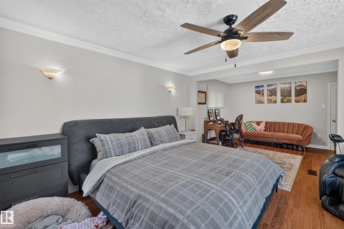 Bedroom featuring wood-finish flooring, a ceiling fan with integrated lighting, crown molding, and sconce lighting - 11015 122 Street, Edmonton, AB 