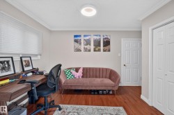 Hardwood-finish flooring featuring a built-in desk with shelving, crown molding, and white trim - 