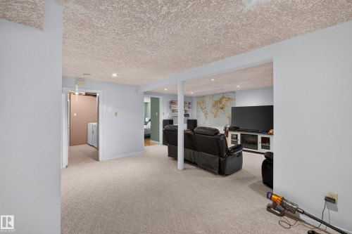 Expansive entertainment area featuring recessed lighting, light-toned carpeting, and a built-in media console with fireplace insert - 11015 122 Street, Edmonton, AB 