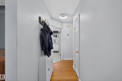Hallway featuring wood-finish flooring, light gray wall paint, and a modern circular flush-mount ceiling light - 