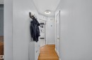 Hallway featuring wood-finish flooring, light gray wall paint, and a modern circular flush-mount ceiling light - 11015 122 Street, Edmonton, AB 