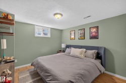 Bedroom featuring light green walls, wood-finish flooring, a white window frame, and a white ceiling with a flush-mount light fixture - 