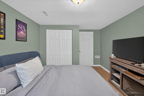 Interior room featuring wood-finish flooring, light green walls, a white textured ceiling, and a flush mount ceiling light fixture - 11015 122 Street, Edmonton, AB 