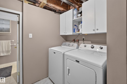 Dedicated laundry area featuring white upper cabinetry, a white washer, and a white dryer - 11015 122 Street, Edmonton, AB 