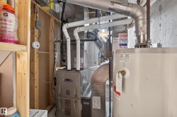 Utility area featuring a Carrier furnace and a water heater, with exposed wood framing and concrete block walls - 