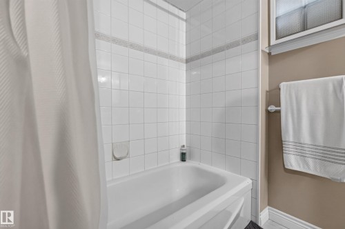 White tiled bath and shower combination with decorative accent tile band - 11015 122 Street, Edmonton, AB 